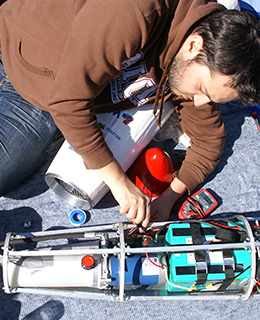 SMaRC team member working with a robot outdoors.